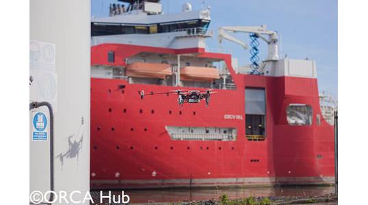 The Imperial College London drone demonstrating autonomous UAV sensor placement on a wind turbine at the ORE Catapult facility in Blyth. The drone is equipped with a winch-tethered magnet and passive wheels capable of perching on, and sliding along, both vertical and horizontal surfaces.