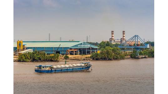 Long Tau River, Vietnam - March 12, 2019: Phuoc Khanh area. Blue river tank vessel sails in front of concrete factory and PetroVietnam power
generation plant chimneys in back. 

Copyright Klodien/AdobeStock