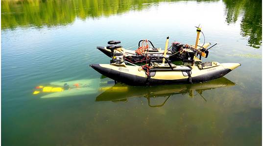A yellow underwater robot (left) finds its way to a mobile docking station to recharge and upload data before continuing a task. (Purdue University photo/Jared Pike)
