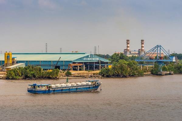 Long Tau River, Vietnam - March 12, 2019: Phuoc Khanh area. Blue river tank vessel sails in front of concrete factory and PetroVietnam power
generation plant chimneys in back. 

Copyright Klodien/AdobeStock